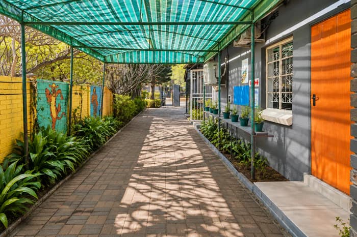 A landscaped covered pathway alongside grey Da Silva Academy buildings.